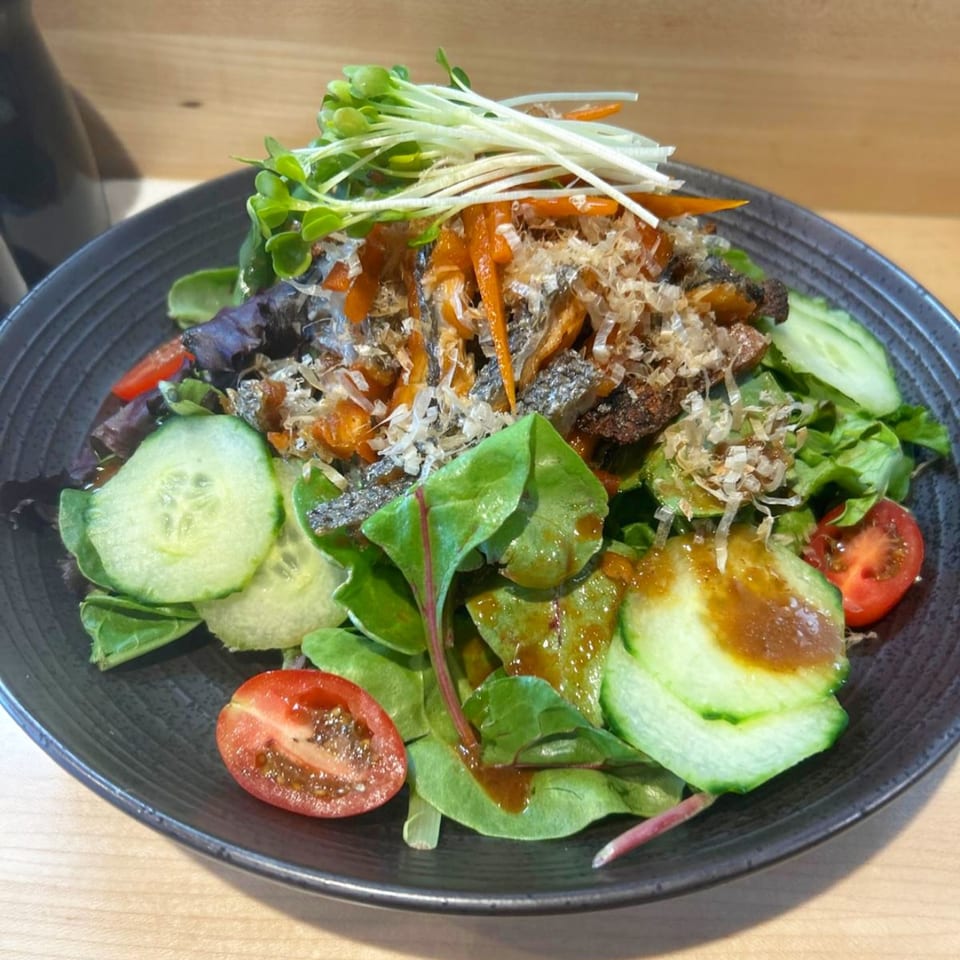 Japanese salad with mixed greens, cucumbers, cherry tomatoes, fish, and bonito flakes.