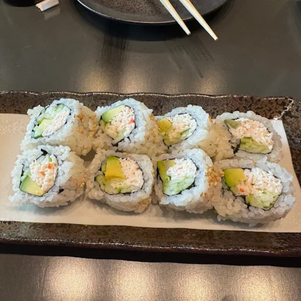 Eight pieces of Hachi sushi rolls with avocado and crab meat on a rectangular plate.