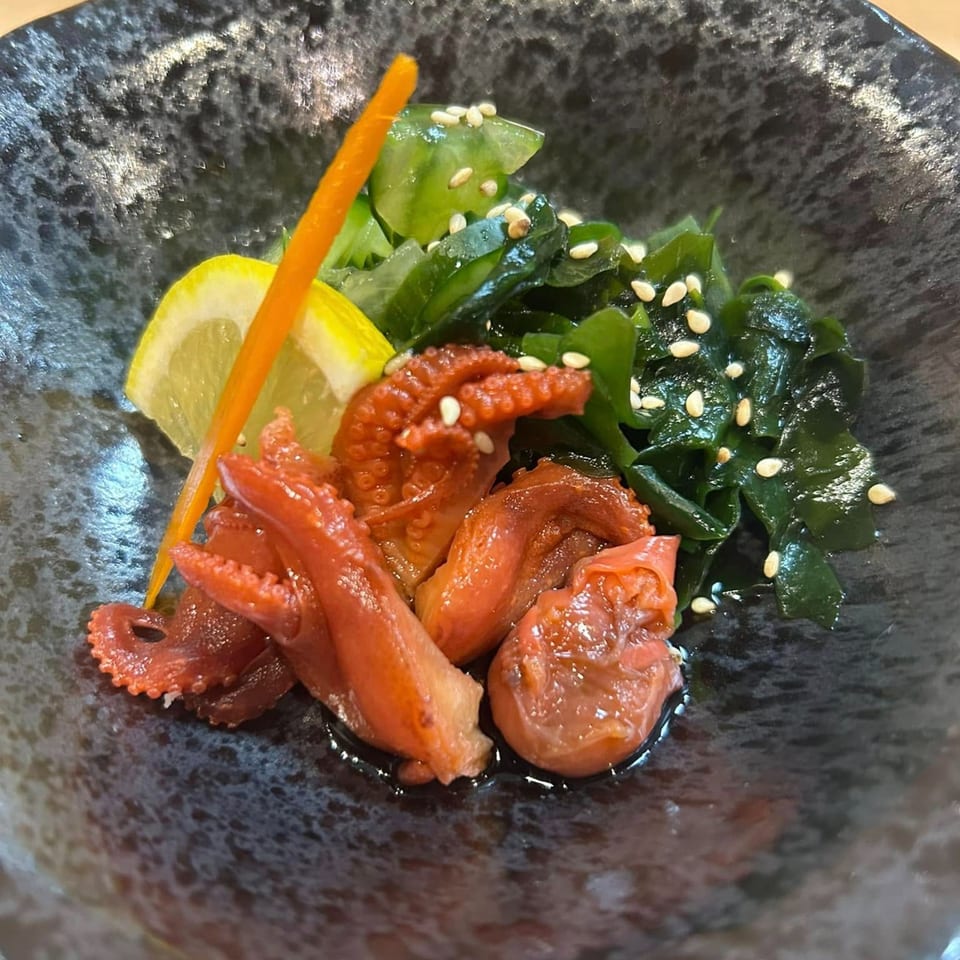 Hachi's Japanese baby octopus salad with seaweed, sesame seeds, lemon, and carrot garnish.