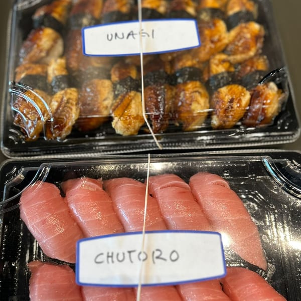 Two plastic containers of sushi, one with unagi and the other with chutoro, ready for takeout.